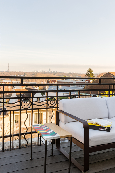 Table basse bois motif en couleurs Origami sur terrasse vue Paris. Collection Meubles Les Pieds Sur La Table