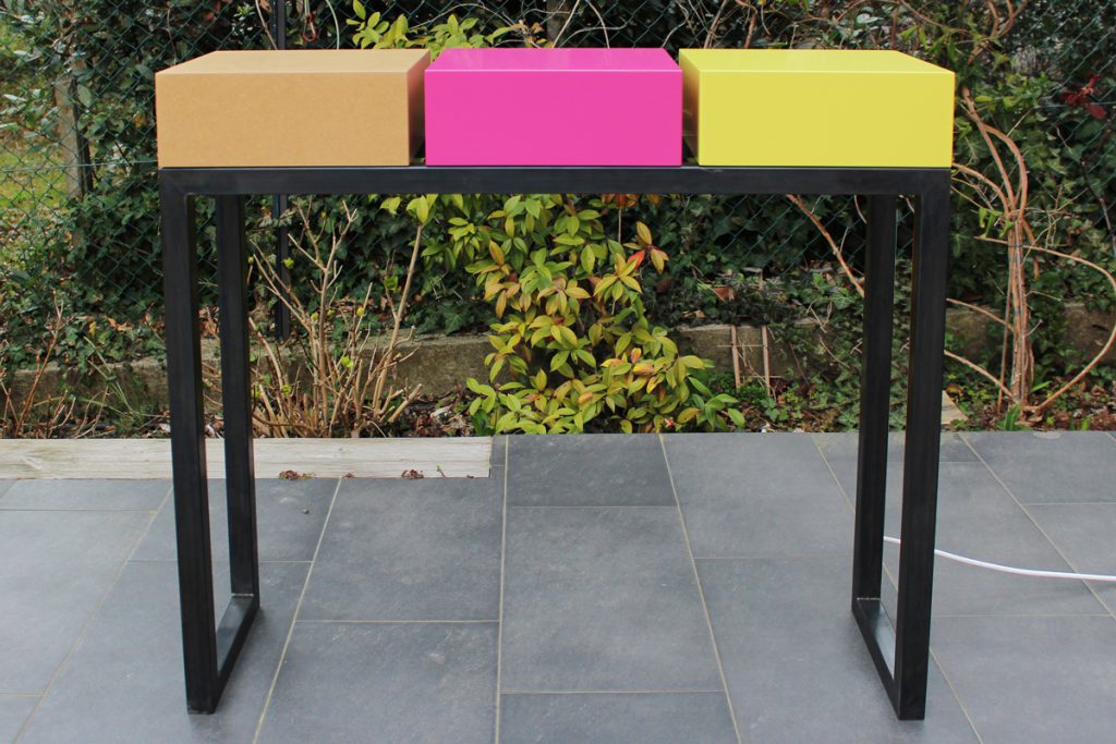 console design connectée avec alimetation électrique en atelier. Console sur mesure, structure en acier patiné, cubes laqués fuchsia, jaune lime et médium vernis. Console moderne Plug&Pied Mobilier design sur mesure Les Pieds Sur La Table